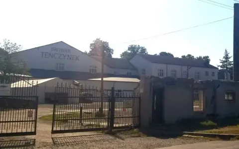 Brama wjazdowa do Browaru Tenczynek. W tle budynki browaru i wysoki komin.