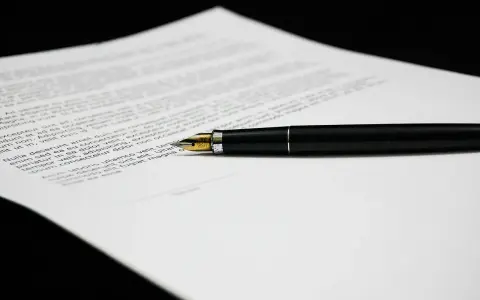 Una penna stilografica nera su un foglio di testo, forse una lettera di richiamo per assenza ingiustificata.