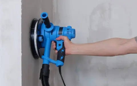 Utensile blu per levigare il muro, ideale per capire come togliere la vernice dal muro.