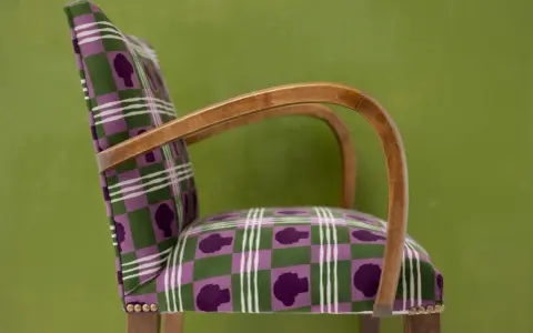 Fauteuil au motif écossais violet et vert, avec des silhouettes de têtes. Un bel exemple d'art tapissier.