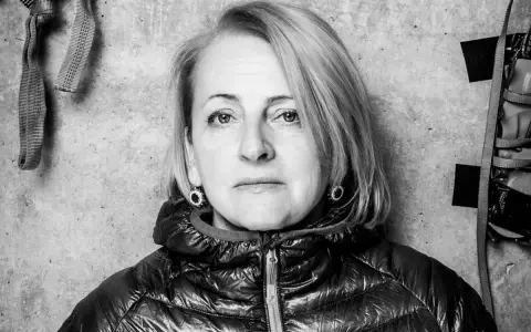 Portret Ewy Berbeki w czarno-białej tonacji, na tle betonowej ściany z elementami wspinaczkowymi.