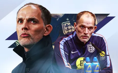 Thomas Tuchel, con su mirada intensa, parece reflexionar sobre la seleccion de Inglaterra. Viste una chaqueta oscura y un chándal con el escudo inglés.