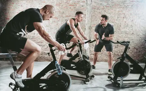 Trainer instructs men on stationary bikes. This workout can help build endurance, proving a stationary bike helps with running.