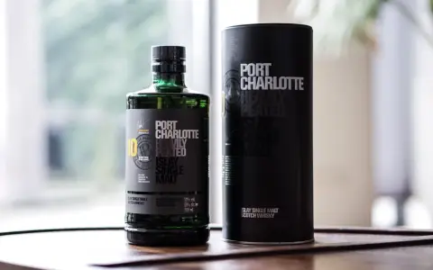 Port Charlotte Heavily Peated 10, whisky single malt z Islay, w zielonej butelce i czarnej tubie.