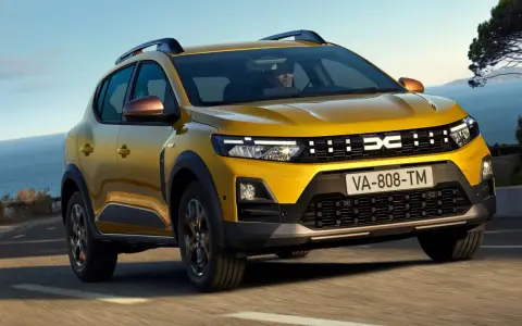 Żółty Dacia Duster, jeden z wielu popularnych dacia modele, jedzie po krętej drodze nad morzem.
