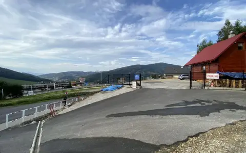 Widok na parking przy górze Żar. W oddali widać zabudowania i góry.