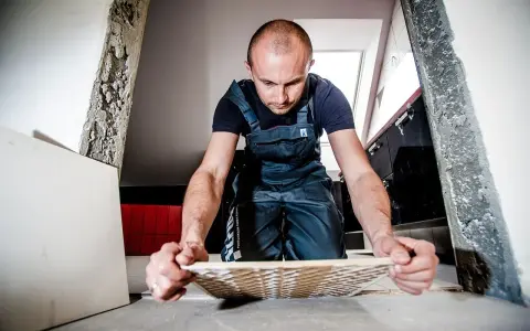 Remont trwa, a mężczyzna w ogrodniczkach zastanawia się, gdzie wyrzucić stare płytki ceramiczne.
