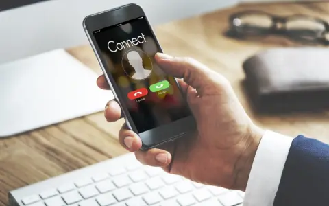 Dłoń trzyma smartfon z ekranem połączenia. Dowiedz się, jak odsłuchać pocztę głosową plus, gdy dzwoni telefon.