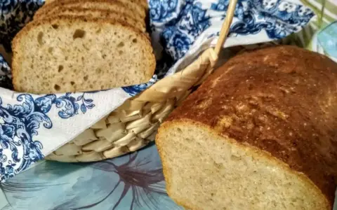 Chleb na piwie, świeżo upieczony, z chrupiącą skórką i puszystym wnętrzem. Kromki w koszyku, ozdobionym niebieskim wzorem.