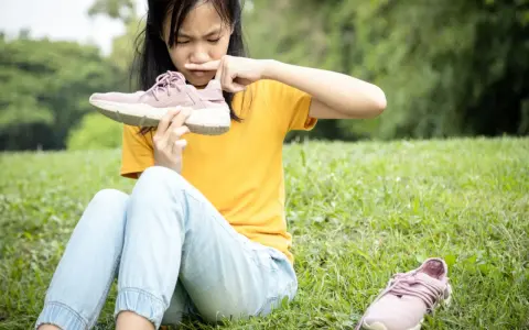 Niña con cara de asco huele un zapato, quizás por el sudor de los pies de niños tras un día de juegos.