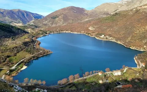 Panoramica del lago di Scanno, con montagne sullo sfondo e case sparse lungo la riva. Un luogo incantevole da esplorare.