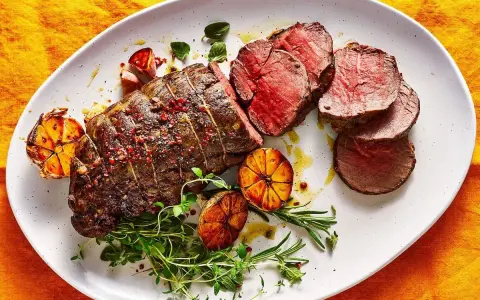 Roast beef al horno jugoso y tierno, servido con ajos asados y hierbas frescas.