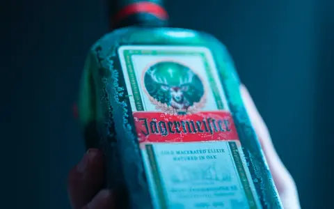 Zimna butelka Jägermeistera, znanego jako "zimny macerowany eliksir dojrzewający w dębie", z charakterystycznym jeleniem na etykiecie.