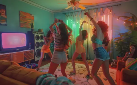 Chicas bailando en una fiesta temática de los 80, con luces de neón y música a todo volumen.