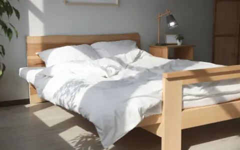 Ein helles Holzbett mit weißer Bettwäsche, das man leicht selber bauen kann. Sonnenschein fällt durch das Fenster.