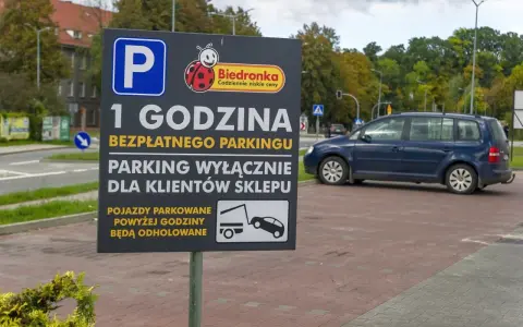 Tablica informuje o 1 godzinie darmowego parkingu dla klientów Biedronki. Pojazdy parkowane dłużej mogą otrzymać mandat za parkowanie i zostać odholowane.