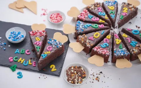 Schokoladenkuchenstücke mit bunten Buchstaben und Zahlen, die "ABC SCHULE" ergeben. Ein perfekter Kuchen zur Einschulung!