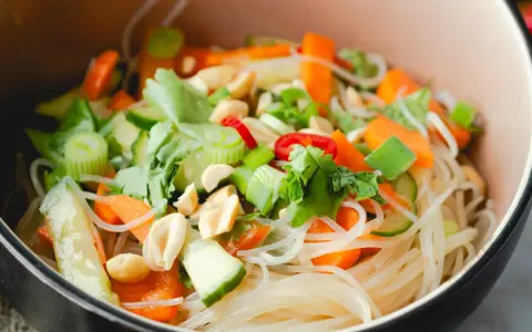 Frischer Glasnudel Salat mit Karotten, Gurken, Frühlingszwiebeln und Erdnüssen in einer Schüssel.