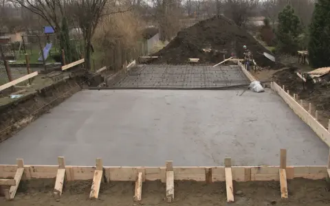 Plac budowy z wylana woda budowlana, zbrojenie i szalunki czekają na dalsze prace.