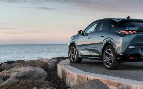 Nowy Peugeot 3008 hybryda na tle spokojnego morza i skalistego wybrzeża.