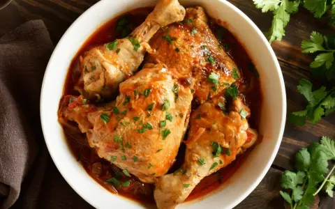 Soczyste kawałki kurczaka w aromatycznym, pomidorowym sosie, posypane świeżą natką pietruszki. Pyszny filet z kurczaka w sosie, gotowy do podania.