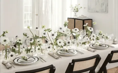 Ett elegant dukat bord med vita anemoneblommor och kristallglas. En diskret detalj är sugrör guld som ger en lyxig touch.
