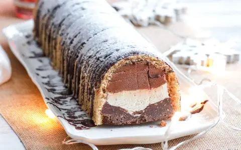 Bûche glacée chocolat, vanille et chocolat, saupoudrée de sucre glace. Une délicieuse recette pour les fêtes.