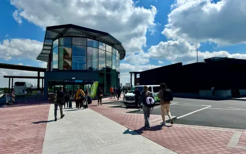 Ludzie z bagażami idą do nowoczesnego terminalu lotniska w Brukseli Charleroi.