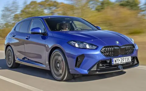 Niebieskie BMW serii 1 (f21) w ruchu, z kierowcą za kierownicą.