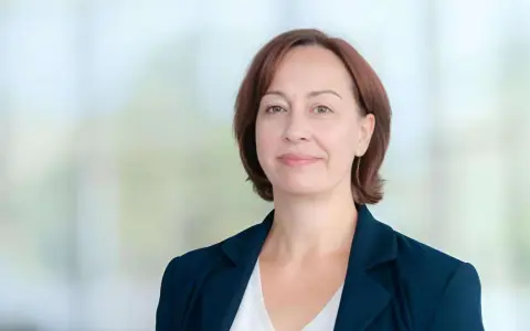 Agata Witkowska, aktorka, w granatowej marynarce i białej bluzce, uśmiecha się lekko.