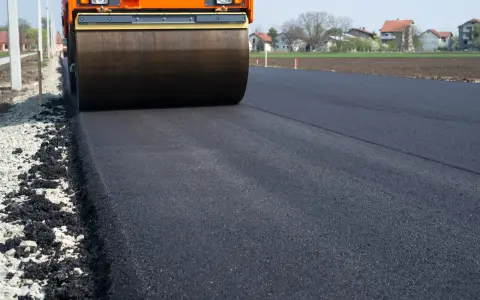 Walec drogowy ugniata świeży asfalt. Zastanawiasz się, ile kosztuje 1m2 asfaltu?