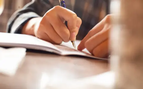 Dłoń pisze piórem na dokumencie, być może podpisując poręczenie na wekslu.