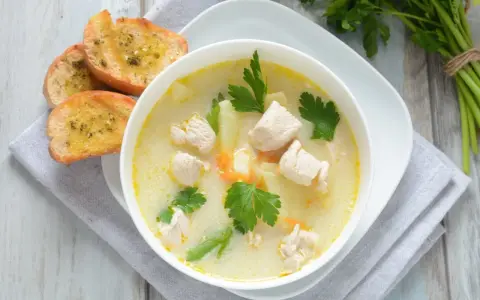 Aromatyczna zupa z kurczakiem z kawałkami mięsa, ziemniaków i marchewki, podana z grzankami czosnkowymi.