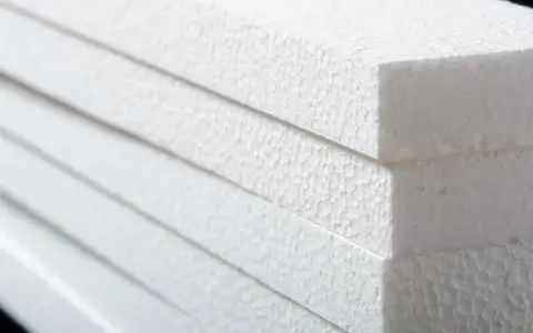 Stapel weißer Styroporplatten, bereit für die Isolierung. Die feine, körnige Textur des Materials ist gut sichtbar.