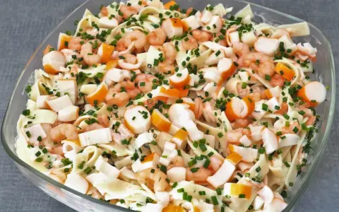 Salade Marco Polo : pâtes, crevettes, bâtonnets de surimi et ciboulette dans un plat en verre.