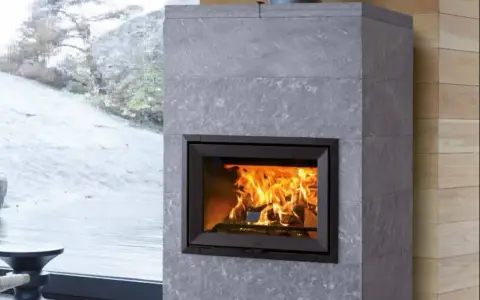 Chimenea moderna de piedra gris con fuego crepitante. Es hora de insertarleña para mantener el calor.
