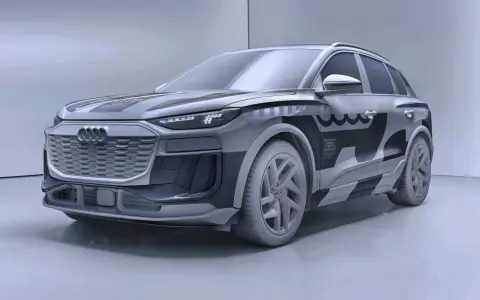 Przyszłościowy Audi Q6 e-tron w szarym kamuflażu, z charakterystycznym grillem i nowoczesnymi światłami LED.