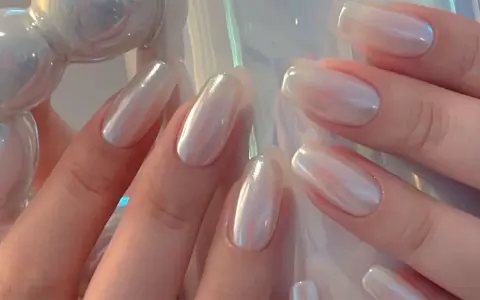 Mani eleganti con unghie a specchio perlate, che riflettono la luce con un effetto iridescente e sofisticato.