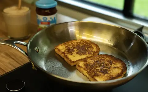 Dos tostadas francesas dorándose en una sartén de acero inoxidable, mostrando las ventajas e inconvenientes de este material para cocinar.