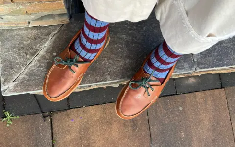 Pies con calcetines a rayas azul y burdeos y mocasines de cuero marrón. Un ejemplo de cómo combinar color teja ropa con estilo.