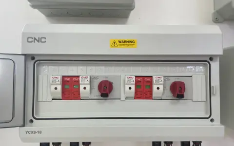 Biała skrzynka elektryczna z czerwonymi przełącznikami i numerowanymi slotami.