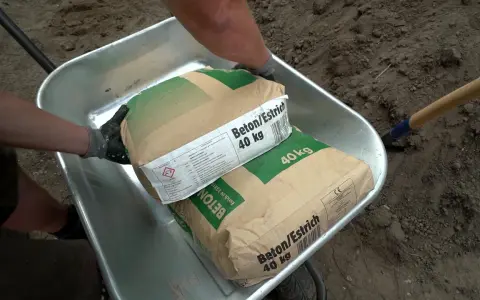 Zwei Säcke Beton/Estrich 40 kg liegen in einer Schubkarre. Verschiedene Estrich Arten sind für Bauprojekte wichtig.
