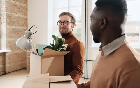 Dos hombres desempaquetan cajas en un nuevo hogar, listos para su movilidad geográfica y la nueva etapa de renta.