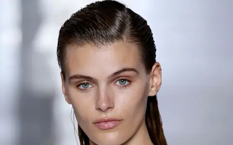 Ein Model mit glänzenden, nassen Haaren im Wet-Look-Stil, das einen intensiven Blick in die Kamera wirft.