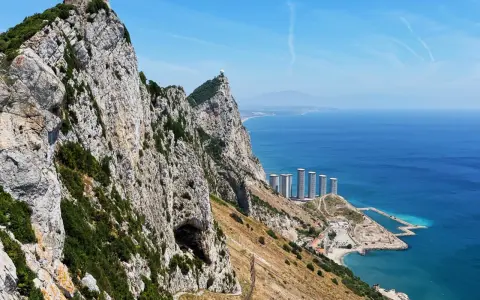 Widok na Skałę Gibraltarską z jaskinią, budynkami i morzem.