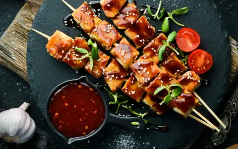 Hähnchenspieße mit glänzender Teriyaki-Sauce, Sesam und Kirschtomaten. Ein köstliches teriyaki sauce rezept zum Nachmachen.