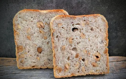 Zwei Scheiben salzarmes Brot mit Nüssen liegen auf Holz.