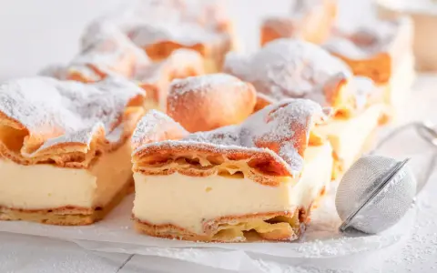 Kremówka papieska, jeden z 10 najlepszych ciast, posypana cukrem pudrem.