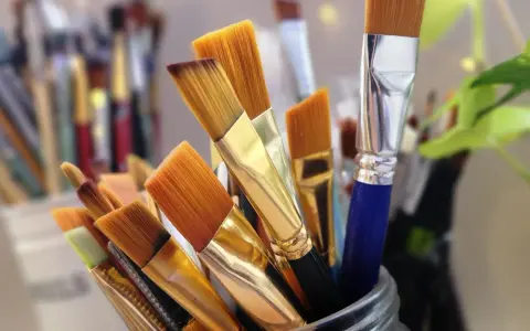 Un assortiment de pinceaux de peinture, prêts pour le nettoyage. Leurs poils orangés et leurs manches dorés brillent, attendant de retrouver leur éclat.