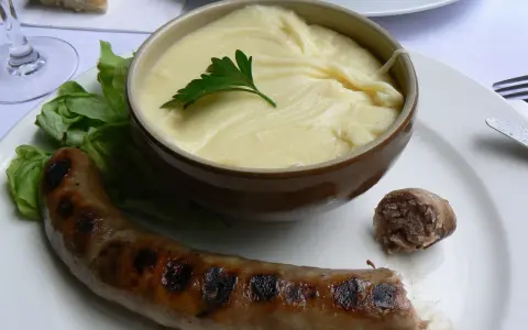 Saucisse grillée et purée onctueuse, un plat traditionnel auvergnat réconfortant.